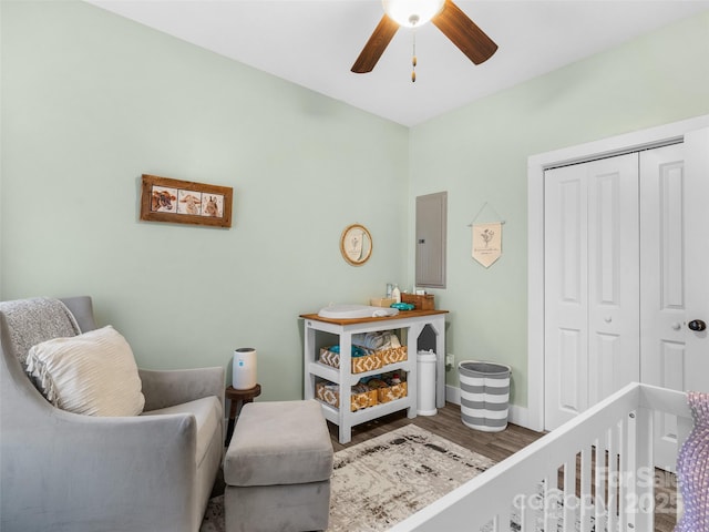 bedroom with ceiling fan, wood finished floors, baseboards, a closet, and electric panel