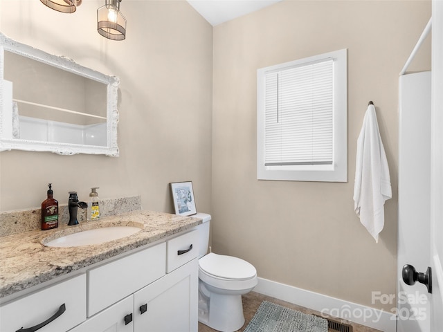 bathroom featuring visible vents, toilet, vanity, baseboards, and walk in shower