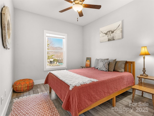 bedroom with a ceiling fan, baseboards, and wood finished floors