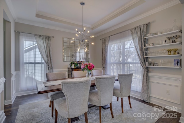 dining area with ornamental molding, a raised ceiling, a notable chandelier, and wood finished floors