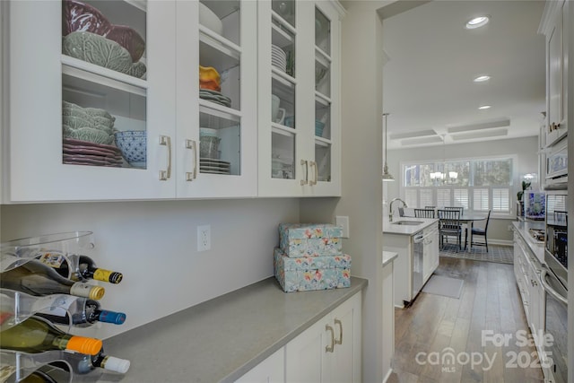 kitchen featuring recessed lighting, wood finished floors, white cabinetry, appliances with stainless steel finishes, and glass insert cabinets