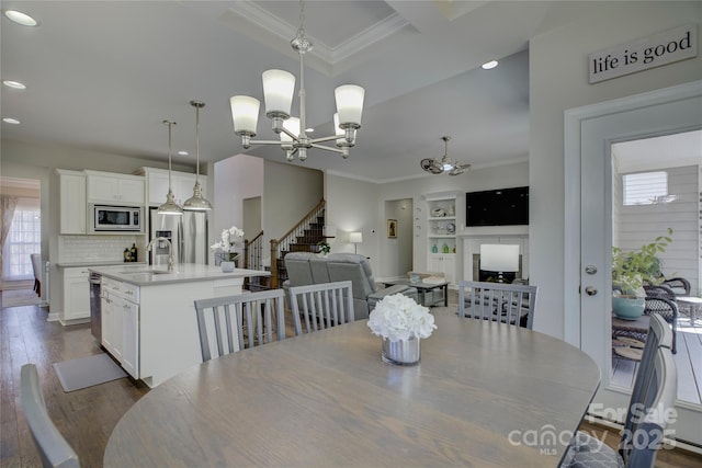 dining room featuring dark wood-style floors, a notable chandelier, crown molding, and stairs