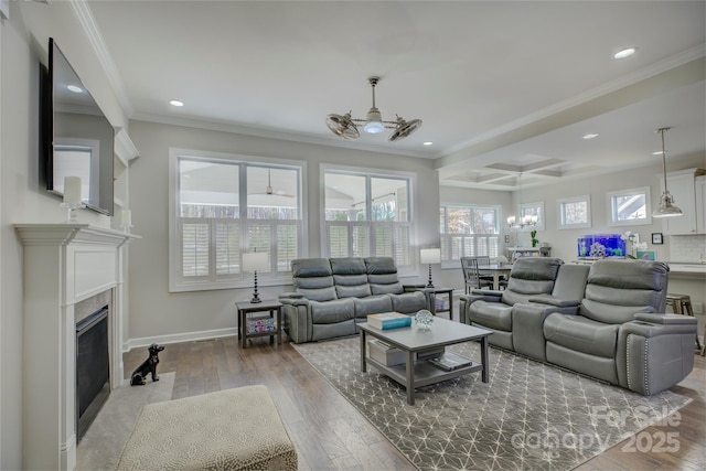 living room with a fireplace with flush hearth, crown molding, baseboards, and wood finished floors