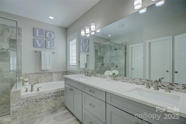 bathroom featuring a bath, a stall shower, double vanity, and a sink