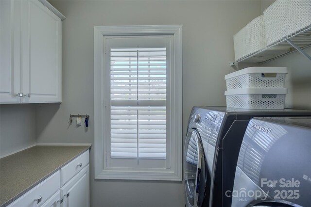 clothes washing area featuring cabinet space and washer and clothes dryer