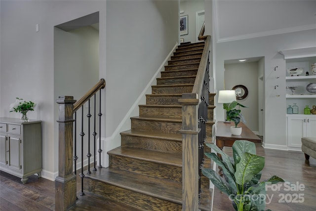 staircase featuring crown molding, wood finished floors, and baseboards