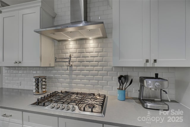 17609 Caddy Ct, Charlotte, NC 28278 - kitchen with light countertops, decorative backsplash, stainless steel gas stovetop, white cabinets, and wall chimney exhaust hood