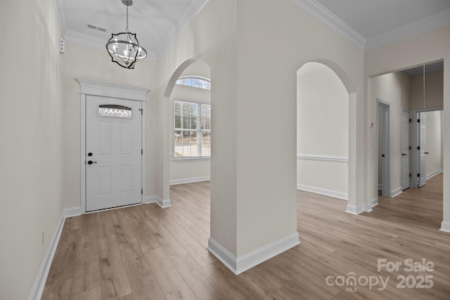 entrance foyer featuring visible vents, arched walkways, light wood-style flooring, and crown molding