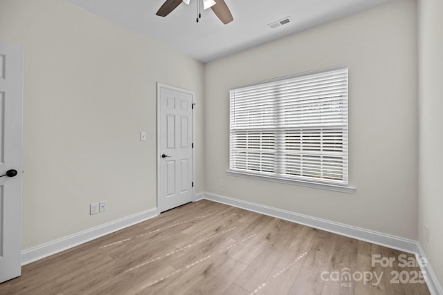 empty room with light wood-style floors, visible vents, ceiling fan, and baseboards