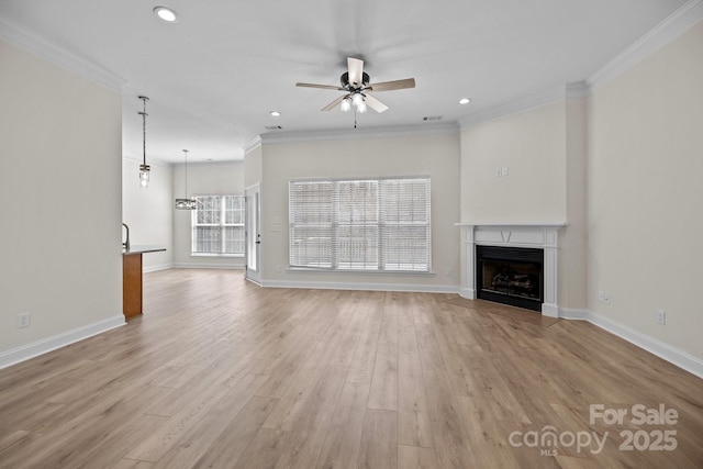 unfurnished living room with light wood-type flooring, ceiling fan, a fireplace, and ornamental molding