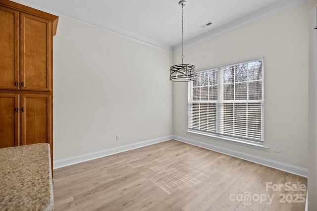 unfurnished dining area featuring light wood finished floors, ornamental molding, visible vents, and baseboards