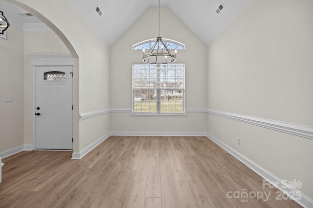 entrance foyer with visible vents, arched walkways, light wood-style flooring, an inviting chandelier, and vaulted ceiling