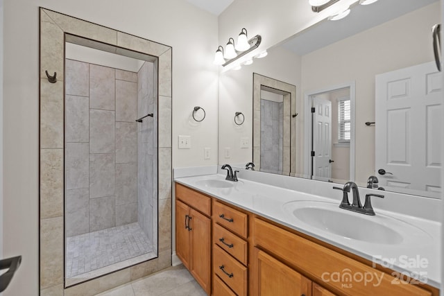 full bath with a tile shower, double vanity, tile patterned flooring, and a sink