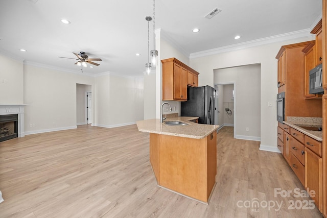 kitchen with brown cabinets, a fireplace, visible vents, a sink, and black appliances