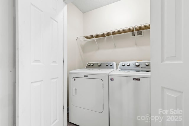 washroom with laundry area, visible vents, and separate washer and dryer