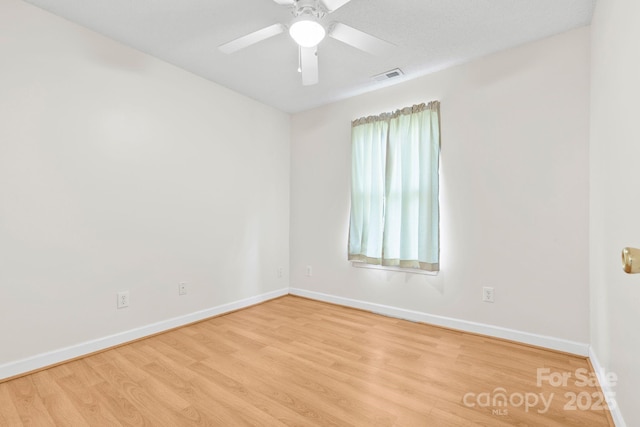 unfurnished room featuring a ceiling fan, visible vents, baseboards, and wood finished floors