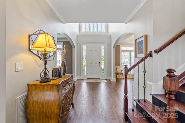 entryway with visible vents, baseboards, stairs, ornamental molding, and wood finished floors