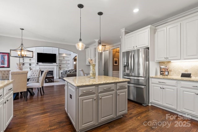 kitchen featuring stainless steel fridge with ice dispenser, arched walkways, white cabinetry, crown molding, and open floor plan