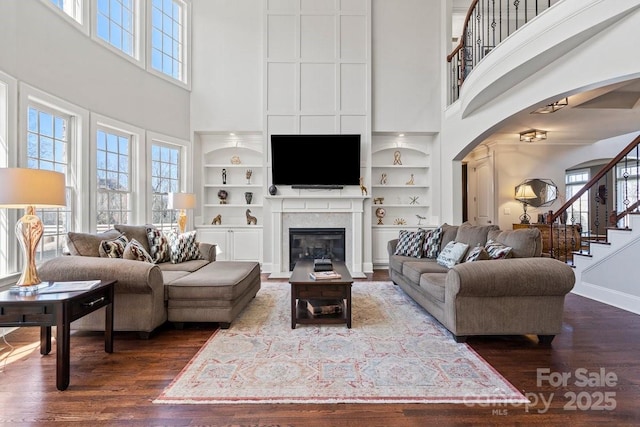 living area with a wealth of natural light, built in features, and dark wood-type flooring