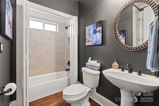 full bath featuring baseboards, toilet, shower / bath combination, wood finished floors, and a sink