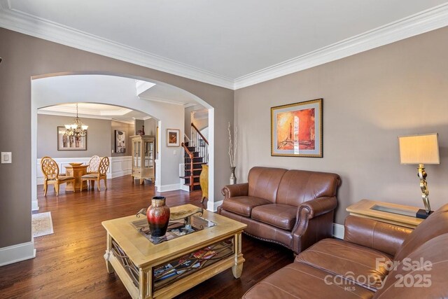 living room featuring arched walkways, crown molding, stairs, and wood finished floors