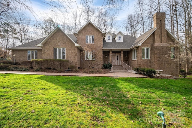 traditional home featuring a shingled roof, a front yard, brick siding, and a chimney