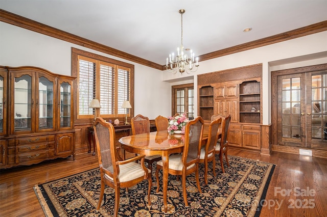 dining room with french doors, dark wood-type flooring, an inviting chandelier, and ornamental molding