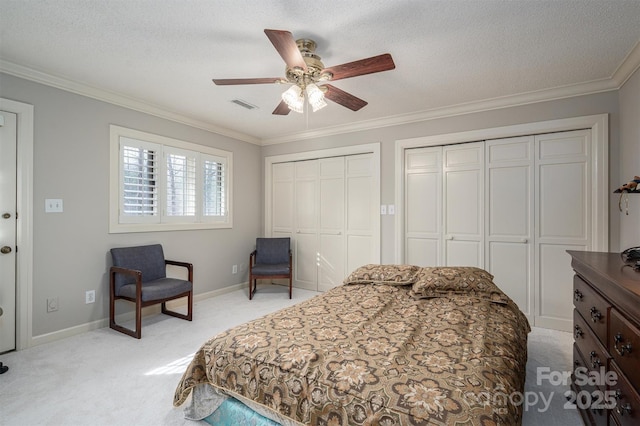 bedroom with visible vents, multiple closets, ornamental molding, a textured ceiling, and light colored carpet