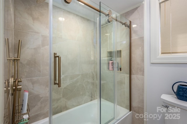 bathroom featuring toilet and shower / bath combination with glass door