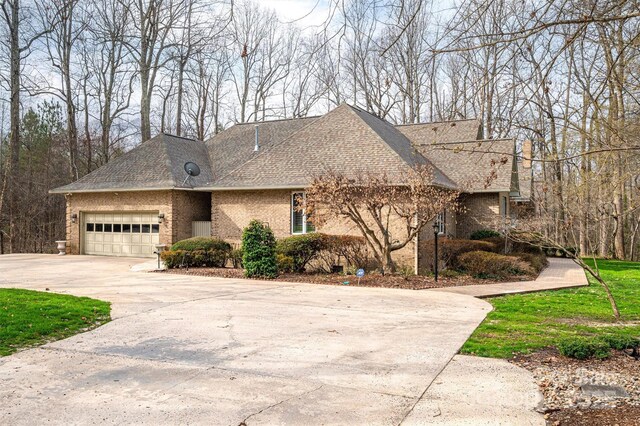 view of front of house featuring brick siding, concrete driveway, a garage, and roof with shingles