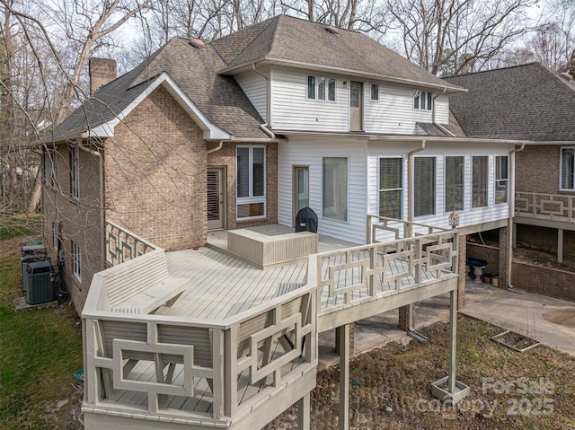 back of property featuring cooling unit, roof with shingles, and a wooden deck