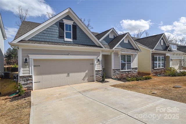 craftsman-style home with stone siding, central AC, and concrete driveway