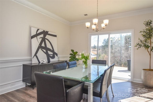 dining space with visible vents, ornamental molding, wainscoting, wood finished floors, and a chandelier