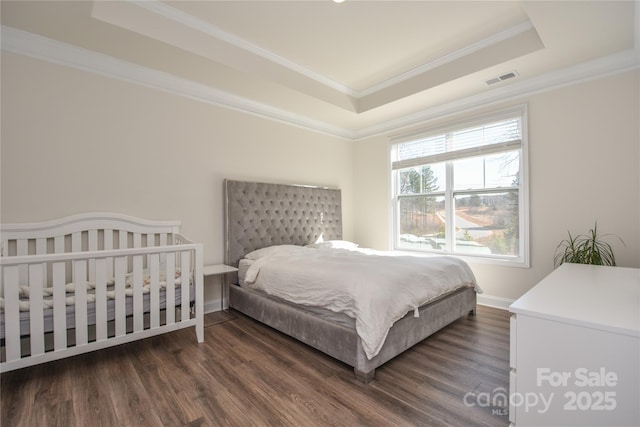 bedroom featuring ornamental molding, a tray ceiling, dark wood-style flooring, and visible vents