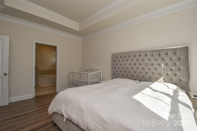 bedroom with a raised ceiling, ornamental molding, connected bathroom, wood finished floors, and baseboards