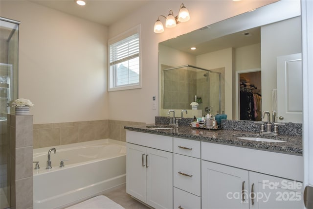 bathroom with a garden tub, a stall shower, a sink, and a walk in closet