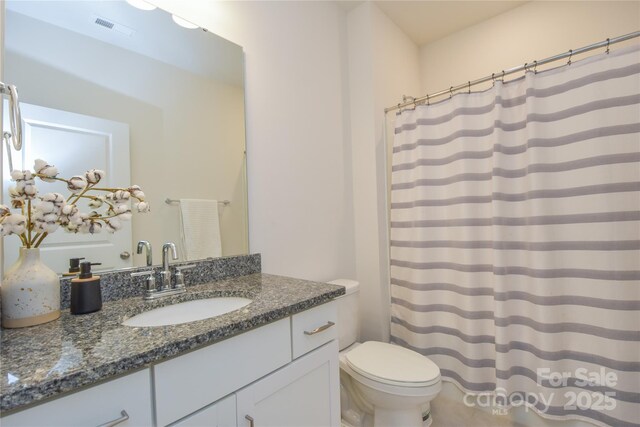 bathroom featuring toilet, curtained shower, vanity, and visible vents