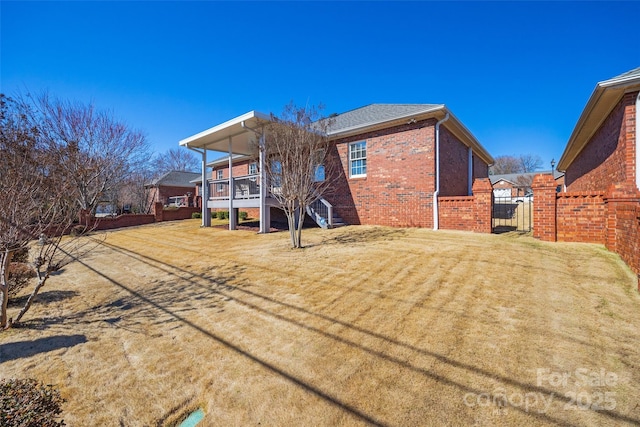 back of property featuring brick siding, stairs, a yard, and fence