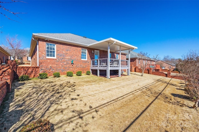 back of house featuring brick siding and roof with shingles