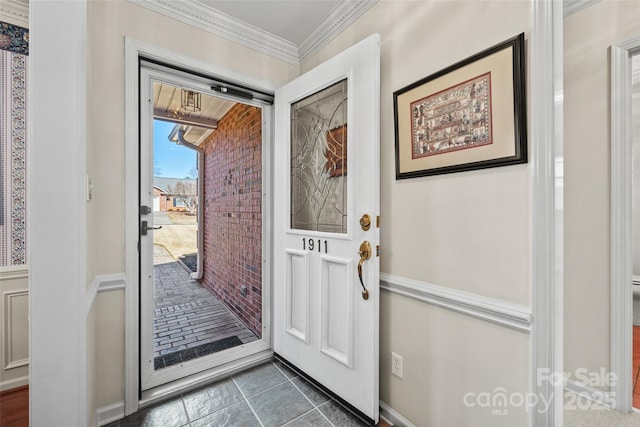 foyer with dark tile patterned floors and ornamental molding