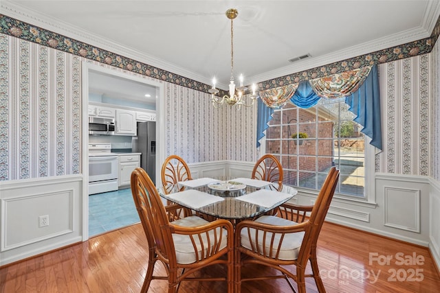 dining room featuring visible vents, wainscoting, wallpapered walls, and light wood-style flooring