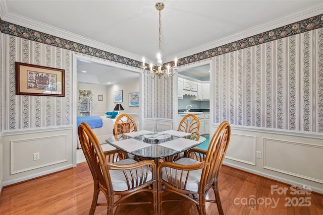 dining area with wallpapered walls, light wood-type flooring, and wainscoting