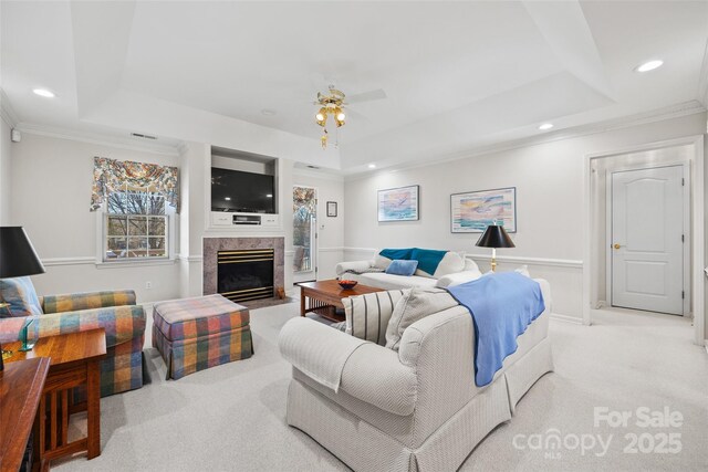 living room with recessed lighting, a tray ceiling, ornamental molding, and a ceiling fan