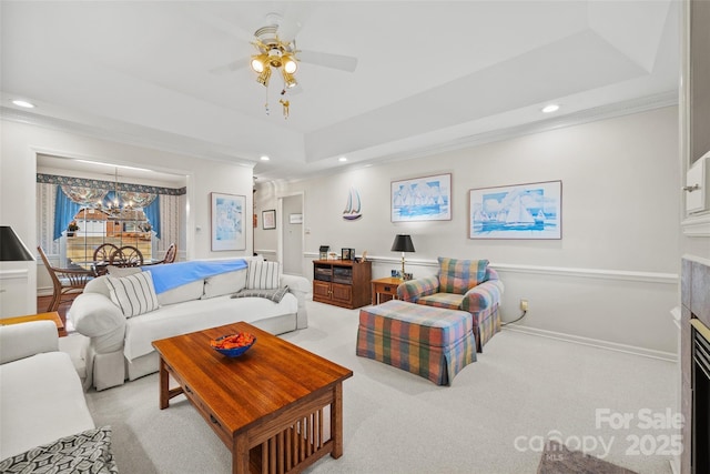 living room featuring light colored carpet, ornamental molding, recessed lighting, a fireplace, and a raised ceiling