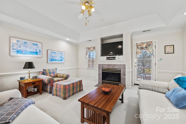 carpeted living room featuring a high end fireplace, visible vents, crown molding, and a raised ceiling