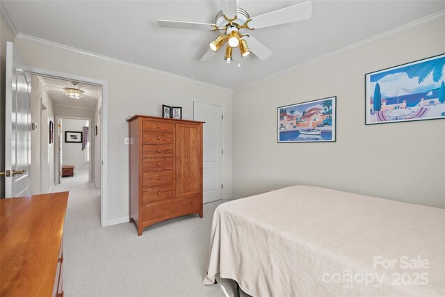 bedroom with crown molding, baseboards, attic access, light carpet, and a ceiling fan