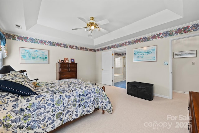 bedroom featuring baseboards, a tray ceiling, carpet floors, and visible vents