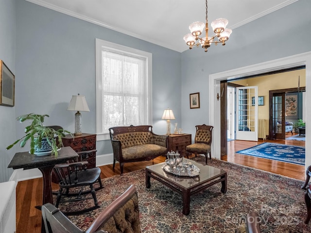 living room featuring a chandelier, ornamental molding, baseboards, and wood finished floors