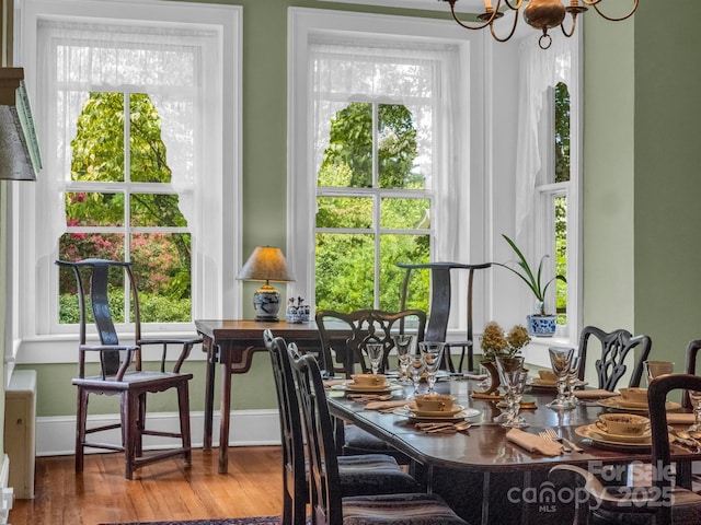 dining room featuring a notable chandelier, baseboards, and wood finished floors