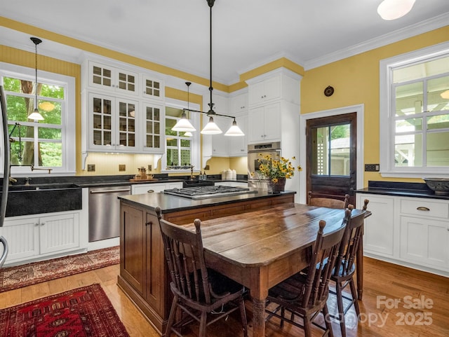 kitchen featuring stainless steel appliances, white cabinets, glass insert cabinets, light wood-style floors, and dark countertops